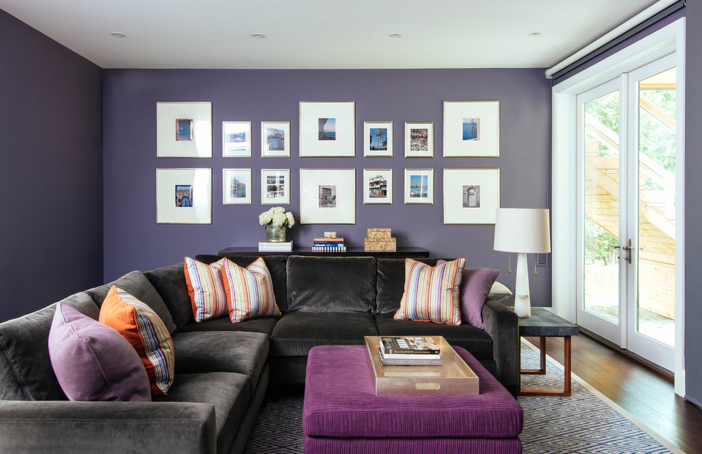 Foto de sala de estar cerrada tradicional renovada grande con paredes púrpuras, suelo de madera en tonos medios, todas las chimeneas, marco de chimenea de piedra, pared multimedia y suelo marrón