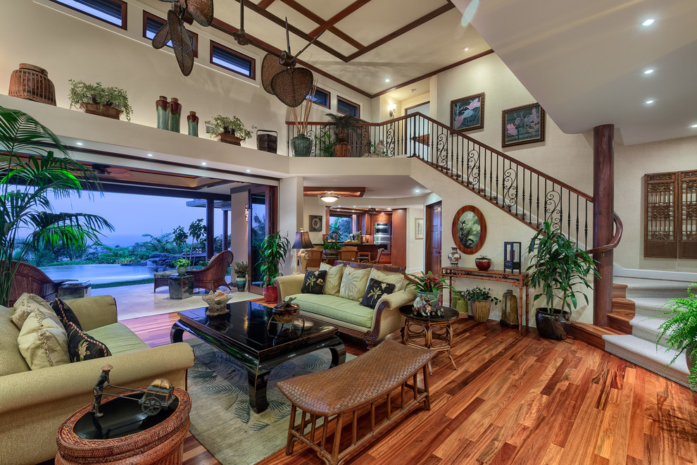 Immagine di un grande soggiorno tropicale aperto con pavimento in legno massello medio