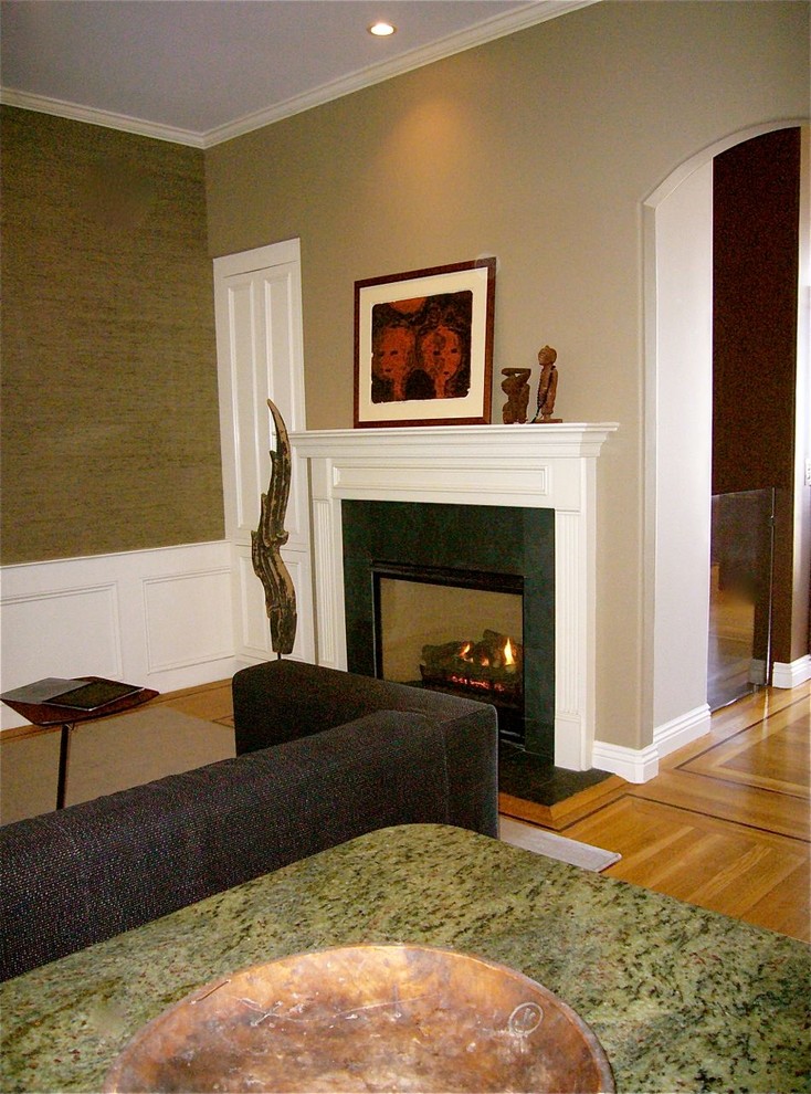 На фото: гостиная комната среднего размера в стиле неоклассика (современная классика) с зелеными стенами, паркетным полом среднего тона, стандартным камином, фасадом камина из камня и телевизором на стене с