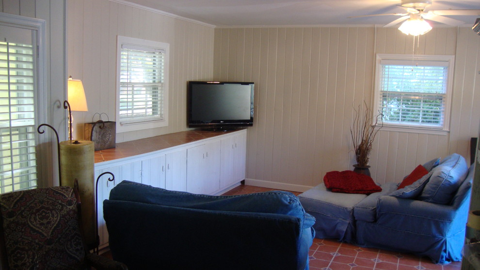 Exemple d'une grande salle de séjour chic ouverte avec un mur beige, tomettes au sol, aucune cheminée et un téléviseur indépendant.
