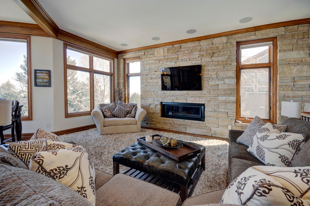 Imagen de sala de estar abierta tradicional renovada de tamaño medio con paredes beige, suelo de madera en tonos medios, todas las chimeneas, marco de chimenea de piedra y televisor colgado en la pared