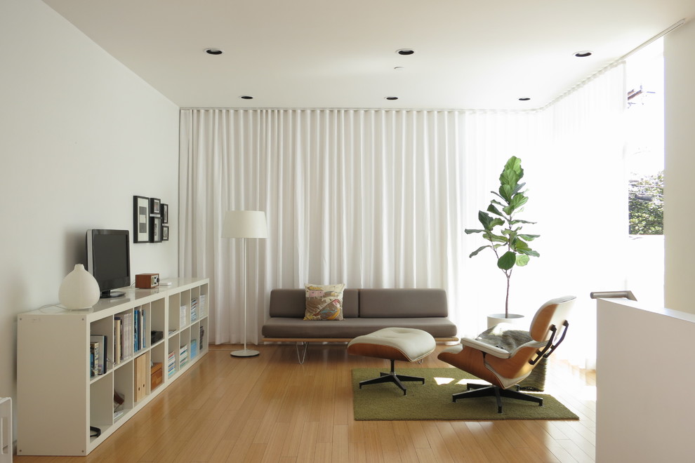 Пример оригинального дизайна: гостиная комната в скандинавском стиле с белыми стенами, светлым паркетным полом, отдельно стоящим телевизором и бежевым полом