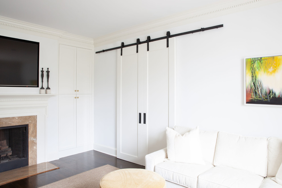 На фото: большая изолированная гостиная комната в стиле неоклассика (современная классика) с белыми стенами, темным паркетным полом, стандартным камином, фасадом камина из дерева, телевизором на стене и коричневым полом с
