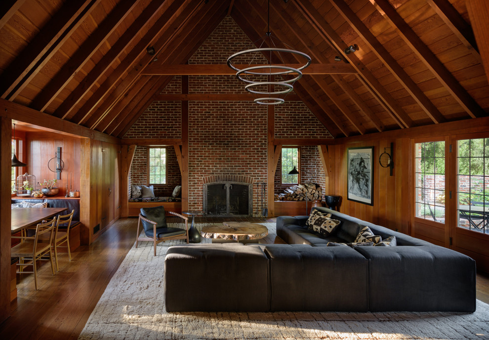 Cette image montre une salle de séjour traditionnelle ouverte avec un mur marron, parquet foncé, une cheminée standard, un manteau de cheminée en brique et un sol marron.