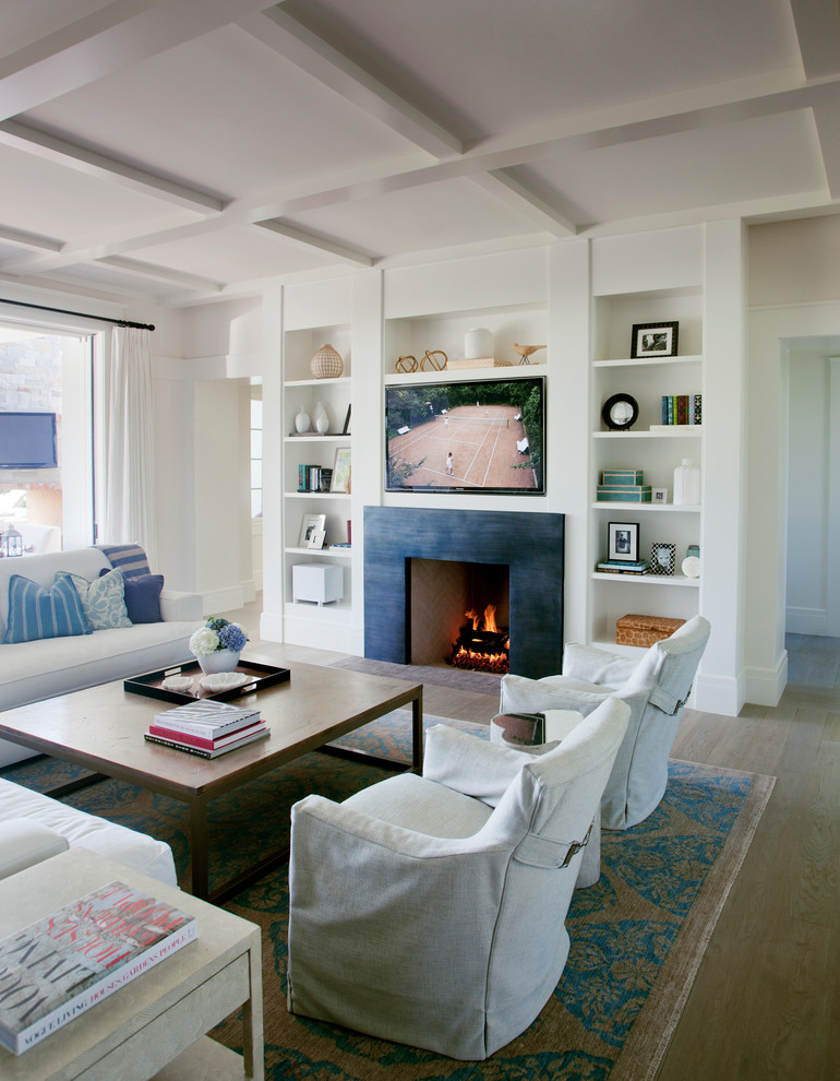 Mid-sized beach style enclosed light wood floor and brown floor family room photo in Los Angeles with white walls, a standard fireplace, a stone fireplace and a media wall