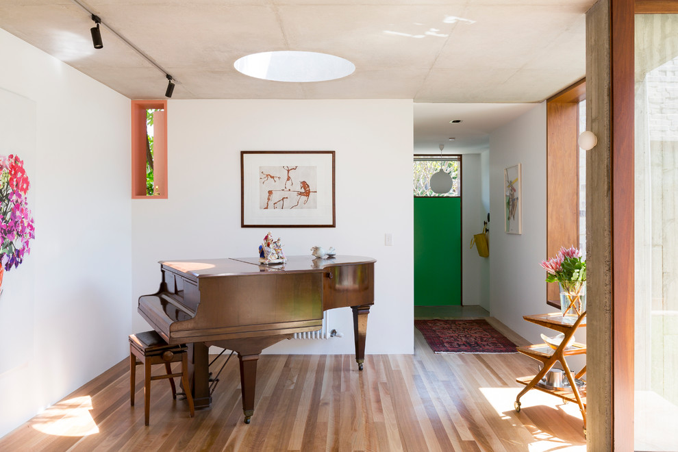 Immagine di un soggiorno design di medie dimensioni con sala della musica, pareti bianche e pavimento in legno massello medio