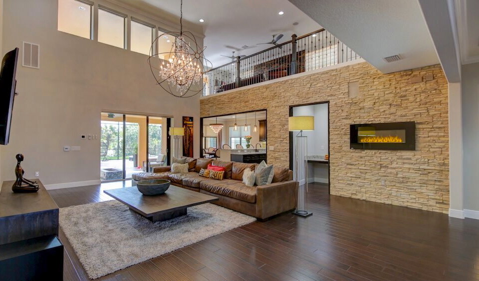 Diseño de sala de estar contemporánea de tamaño medio con paredes beige, suelo de madera oscura, televisor colgado en la pared, chimenea lineal y marco de chimenea de piedra