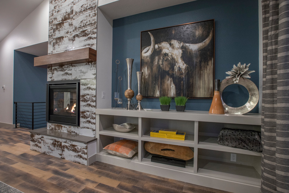 Idée de décoration pour une salle de séjour design de taille moyenne et ouverte avec un mur gris, un sol en bois brun, une cheminée double-face, un manteau de cheminée en carrelage et un sol marron.
