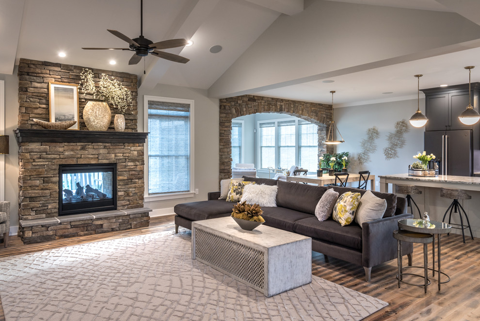 Large arts and crafts open concept medium tone wood floor and multicolored floor family room photo in Other with gray walls, a two-sided fireplace, a stone fireplace and a tv stand
