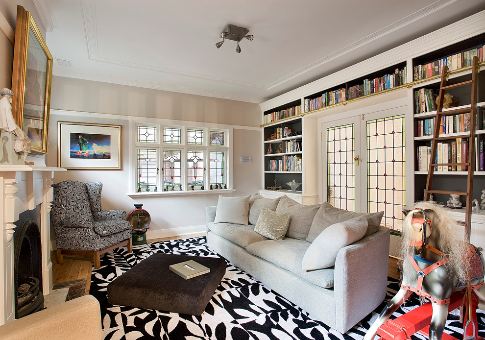 Ejemplo de sala de estar con biblioteca cerrada bohemia con paredes beige, suelo de madera en tonos medios y todas las chimeneas