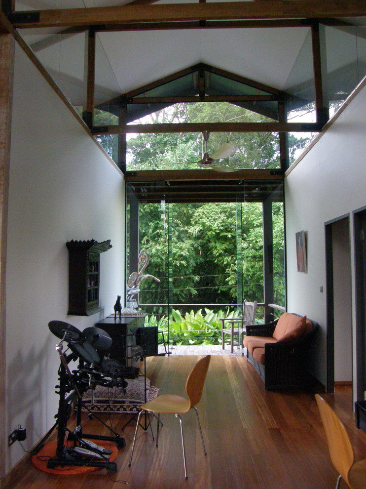 Idéer för små tropiska allrum på loftet, med ett musikrum, vita väggar, mellanmörkt trägolv och brunt golv