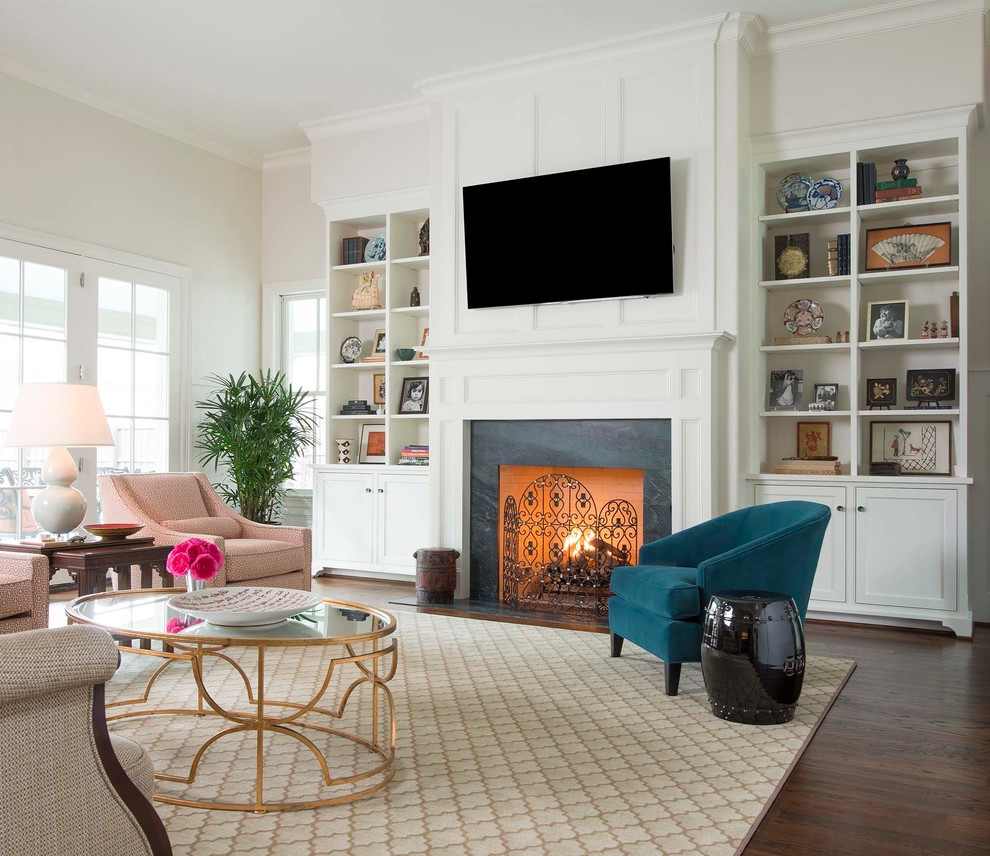 Offenes Klassisches Wohnzimmer mit grauer Wandfarbe, dunklem Holzboden, Kamin, Kaminumrandung aus Stein und TV-Wand in Dallas