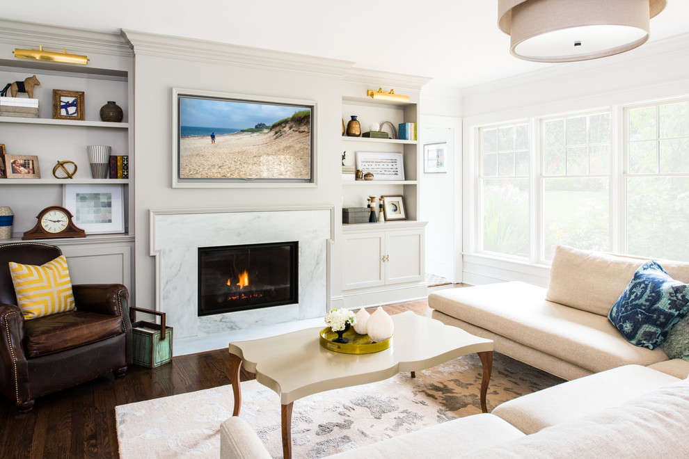 Cette image montre une salle de séjour traditionnelle avec un mur gris, parquet foncé, une cheminée standard, un manteau de cheminée en pierre et un téléviseur encastré.