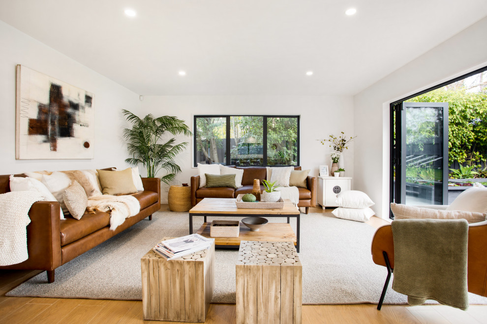 Example of a trendy open concept medium tone wood floor and brown floor living room design in Auckland with white walls