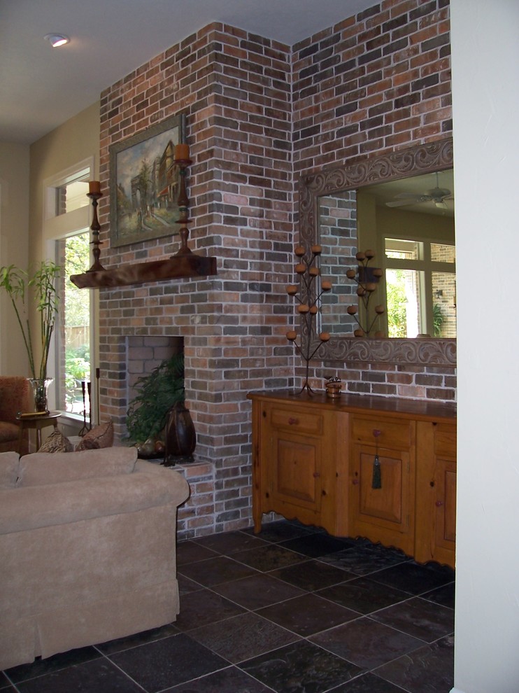 Стильный дизайн: большая открытая гостиная комната в классическом стиле с бежевыми стенами, полом из сланца, стандартным камином и фасадом камина из кирпича - последний тренд