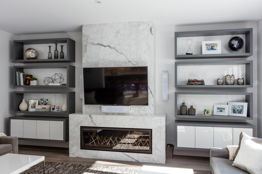 Ejemplo de sala de estar actual de tamaño medio con paredes blancas, suelo de madera en tonos medios, chimenea lineal, marco de chimenea de piedra y televisor colgado en la pared