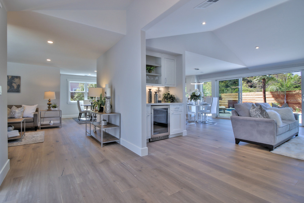 Offenes Modernes Wohnzimmer mit grauer Wandfarbe, hellem Holzboden, Kamin, Kaminumrandung aus Stein und grauem Boden in San Francisco