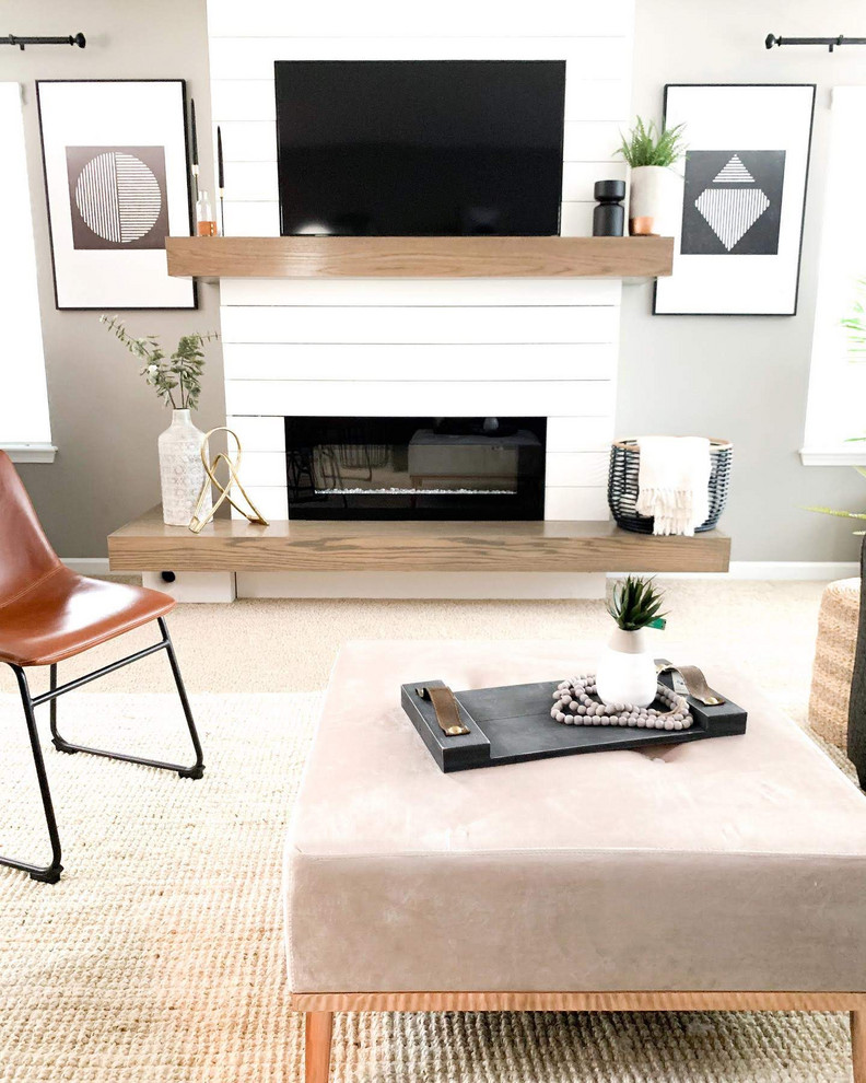 Exempel på ett modernt allrum med öppen planlösning, med vita väggar, heltäckningsmatta, en standard öppen spis, en spiselkrans i trä, en väggmonterad TV och beiget golv