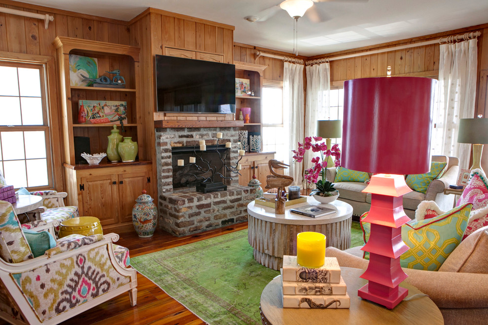 Example of a mid-sized beach style open concept medium tone wood floor family room design in Charleston with brown walls, a standard fireplace, a brick fireplace and a wall-mounted tv