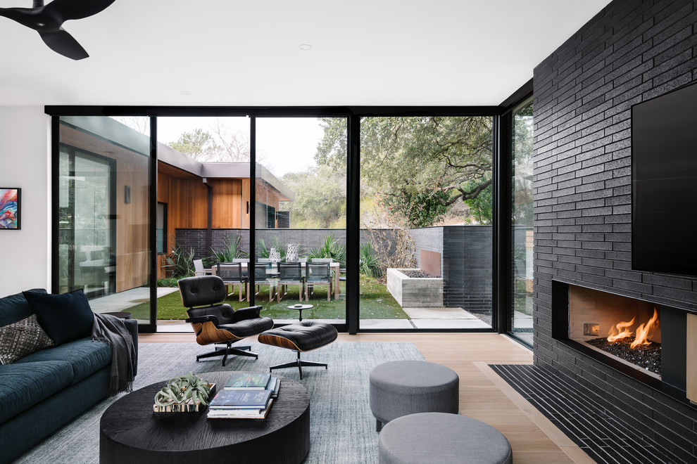Offenes Modernes Wohnzimmer mit schwarzer Wandfarbe, hellem Holzboden, Gaskamin und TV-Wand in Austin