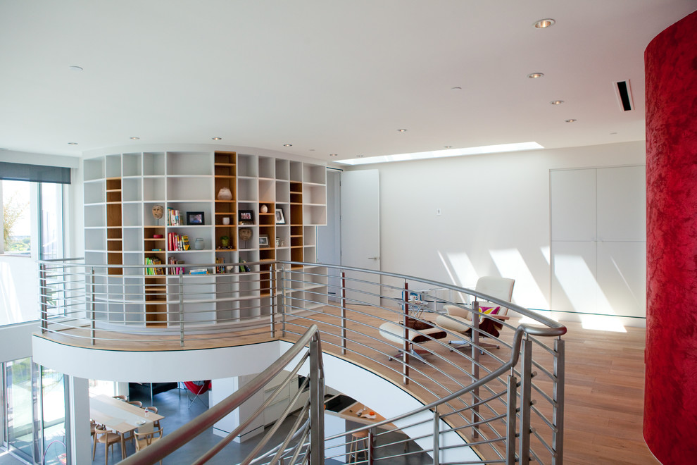 Diseño de sala de estar con biblioteca tipo loft contemporánea de tamaño medio sin chimenea y televisor con paredes blancas, suelo de madera en tonos medios y suelo beige