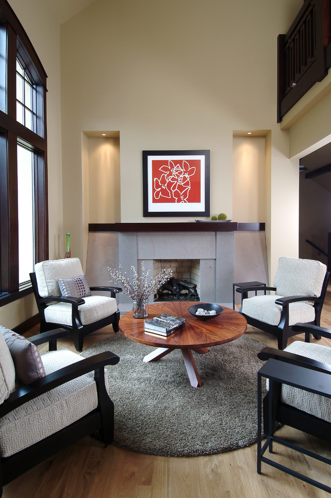 Imagen de sala de estar con biblioteca abierta clásica pequeña con paredes beige, suelo de madera clara, todas las chimeneas, marco de chimenea de hormigón y alfombra