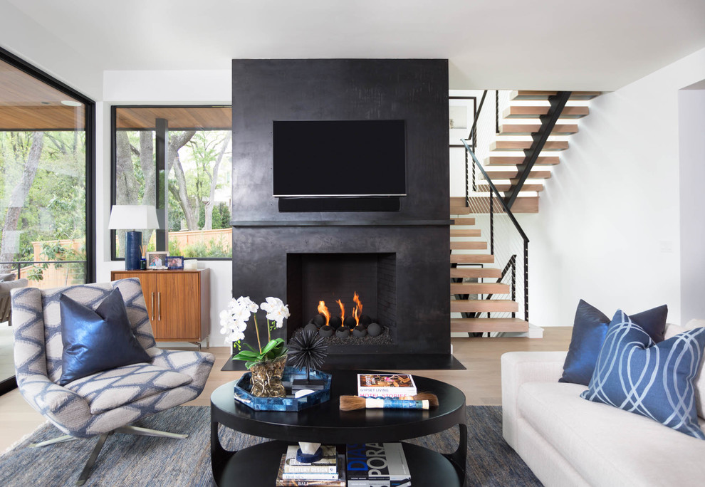 Foto de sala de estar abierta, actual, de tamaño medio, con suelo de madera clara, todas las chimeneas, marco de chimenea de hormigón, televisor colgado en la pared, suelo beige y paredes negras