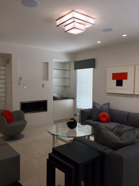 Exemple d'une grande salle de séjour moderne ouverte avec salle de jeu, un mur blanc, parquet peint, une cheminée standard, un manteau de cheminée en plâtre, un téléviseur encastré et un sol gris.