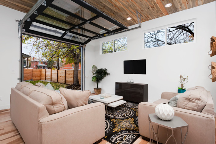 Modelo de sala de estar abierta industrial grande con paredes blancas, suelo de madera clara, todas las chimeneas y televisor colgado en la pared