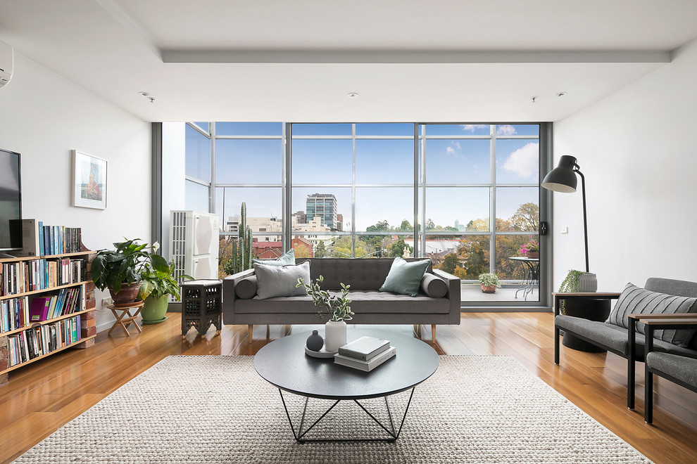 Foto de sala de estar moderna con paredes blancas, suelo de madera clara y televisor independiente