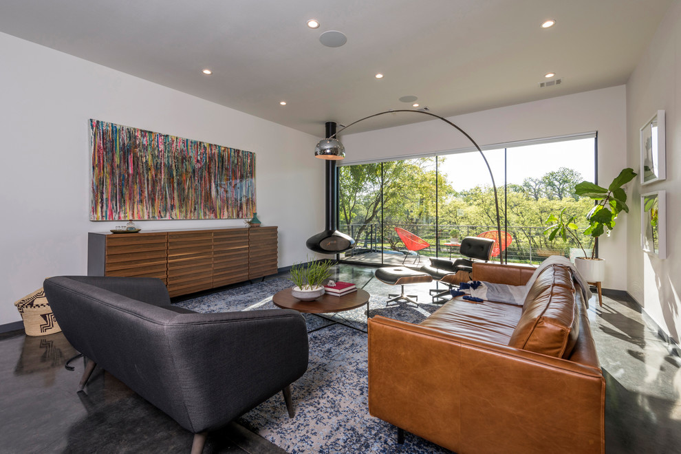 На фото: гостиная комната среднего размера в стиле модернизм с белыми стенами, бетонным полом, подвесным камином, скрытым телевизором и серым полом