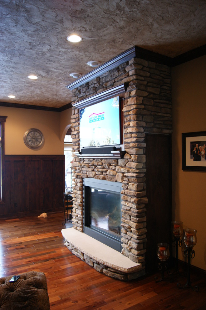 Foto de sala de estar abierta tradicional pequeña con paredes beige, suelo de madera en tonos medios, todas las chimeneas, marco de chimenea de ladrillo y televisor colgado en la pared