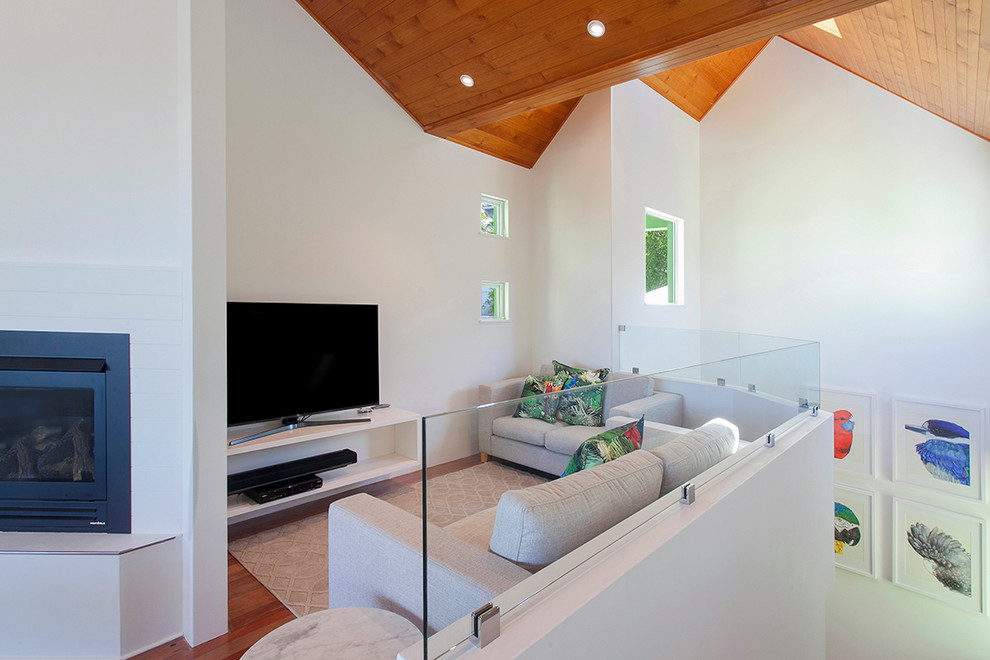 Diseño de sala de estar marinera pequeña con paredes blancas, suelo de madera en tonos medios, chimenea de esquina y televisor independiente
