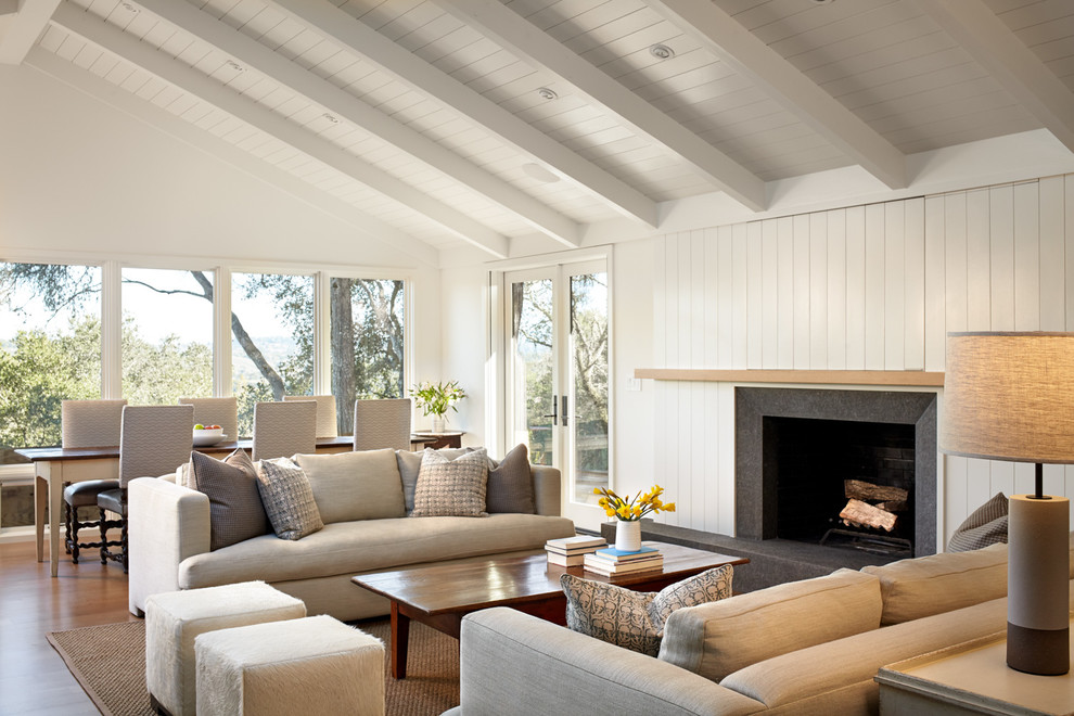 Imagen de sala de estar abierta tradicional renovada con paredes blancas, suelo de madera en tonos medios, todas las chimeneas y televisor retractable