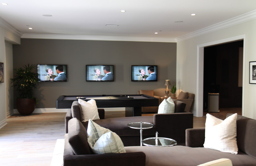 На фото: открытая комната для игр в современном стиле с серыми стенами, светлым паркетным полом и телевизором на стене без камина