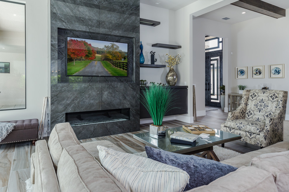 Свежая идея для дизайна: большая открытая гостиная комната в современном стиле с серыми стенами, полом из керамогранита, стандартным камином, фасадом камина из плитки, телевизором на стене и разноцветным полом - отличное фото интерьера