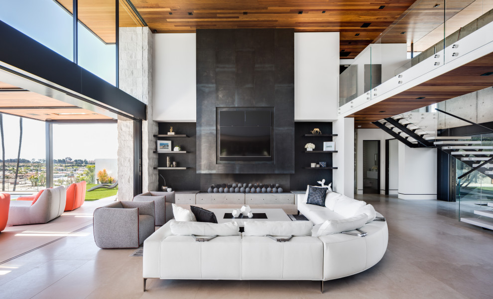 Modelo de sala de estar abierta contemporánea con paredes blancas, chimenea lineal, televisor colgado en la pared y suelo beige