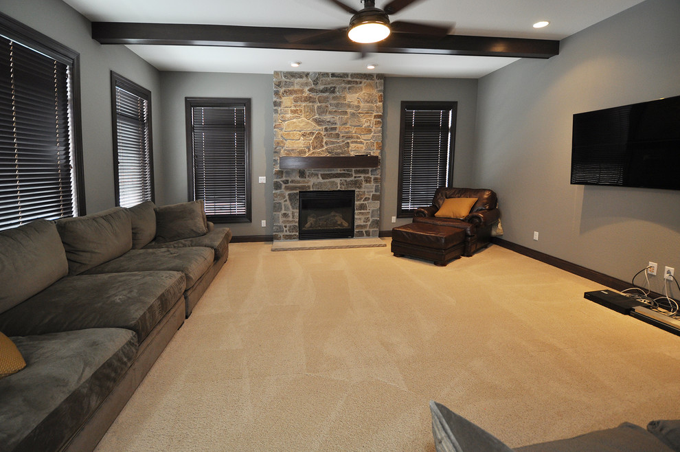На фото: изолированная гостиная комната среднего размера в стиле фьюжн с серыми стенами, ковровым покрытием, стандартным камином, фасадом камина из камня и телевизором на стене с