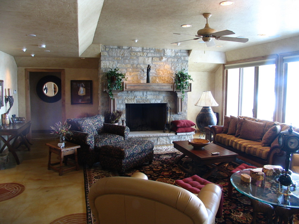 На фото: большая открытая гостиная комната в стиле кантри с домашним баром, разноцветными стенами, бетонным полом, стандартным камином и фасадом камина из камня с