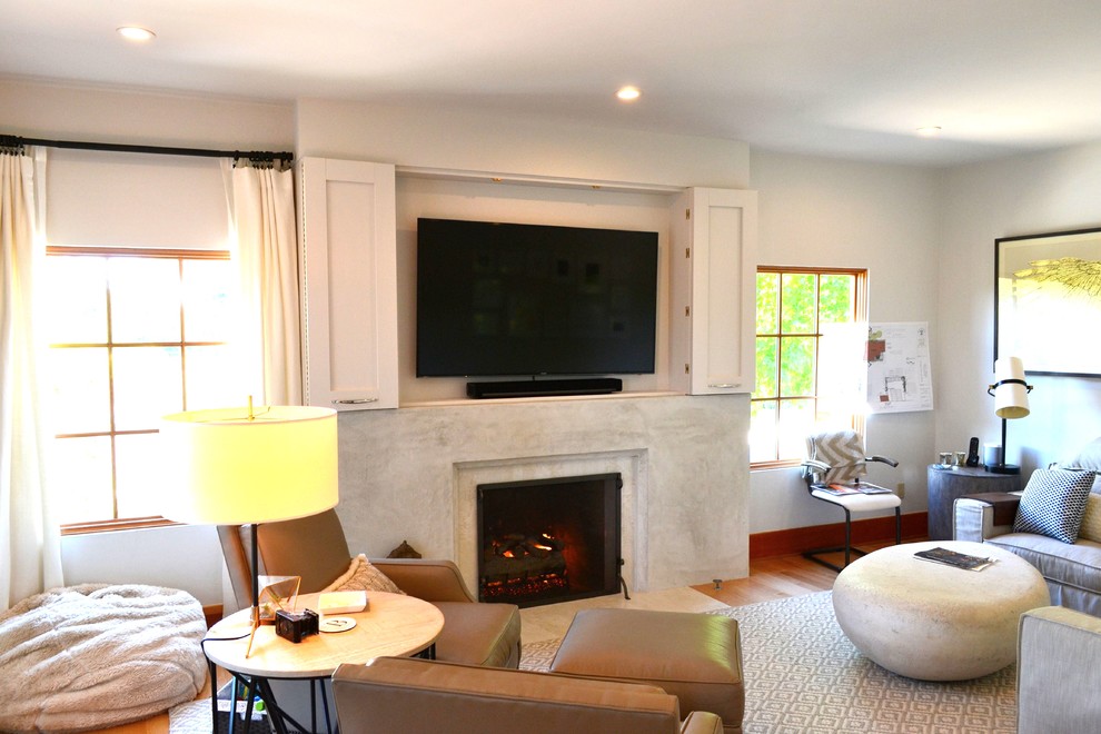 Cette photo montre une salle de séjour moderne de taille moyenne et fermée avec un mur blanc, parquet clair, une cheminée standard, un manteau de cheminée en béton, un téléviseur dissimulé et éclairage.