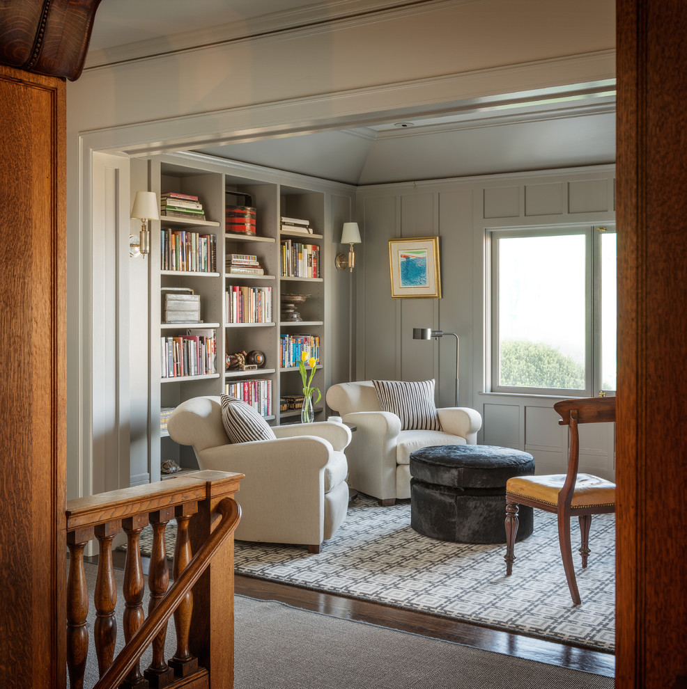 На фото: гостиная комната в стиле неоклассика (современная классика) с с книжными шкафами и полками, серыми стенами, темным паркетным полом и ковром на полу