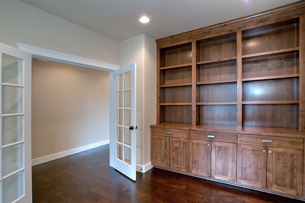 Foto de sala de estar con biblioteca cerrada clásica con paredes beige, suelo de madera oscura y suelo marrón