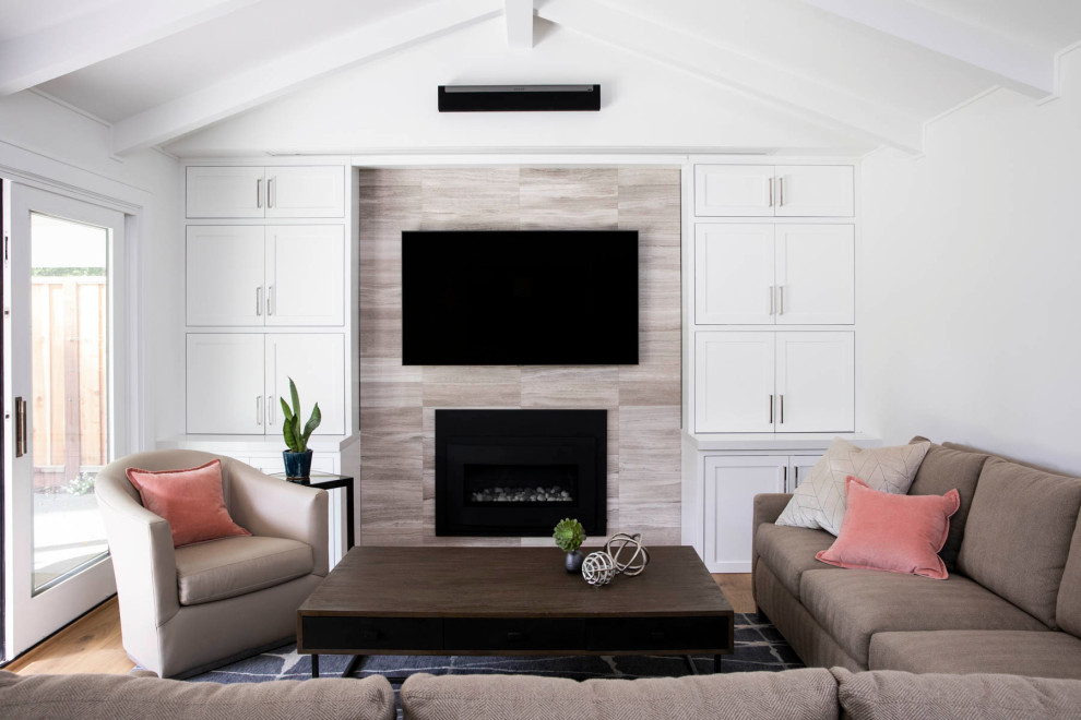 Exempel på ett modernt allrum, med vita väggar, mellanmörkt trägolv, en standard öppen spis, en spiselkrans i trä, en väggmonterad TV och brunt golv
