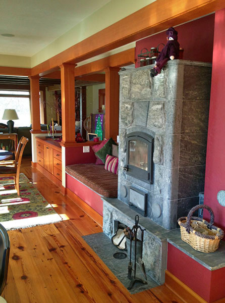 Ispirazione per un soggiorno tradizionale di medie dimensioni con pareti rosse, parquet chiaro, stufa a legna e cornice del camino in pietra