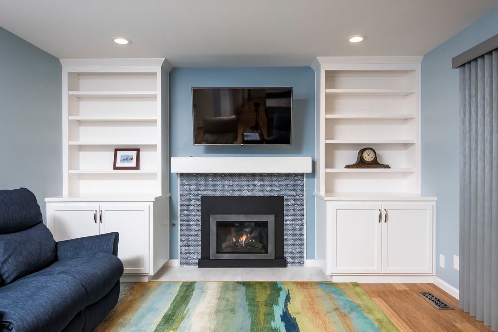 На фото: открытая гостиная комната среднего размера в стиле неоклассика (современная классика) с синими стенами, полом из бамбука, стандартным камином, фасадом камина из камня, телевизором на стене и коричневым полом