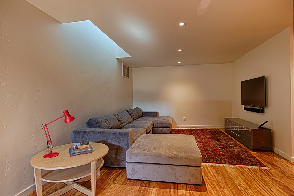 Immagine di un soggiorno design di medie dimensioni e chiuso con pareti grigie, parquet chiaro, nessun camino, TV a parete e pavimento beige