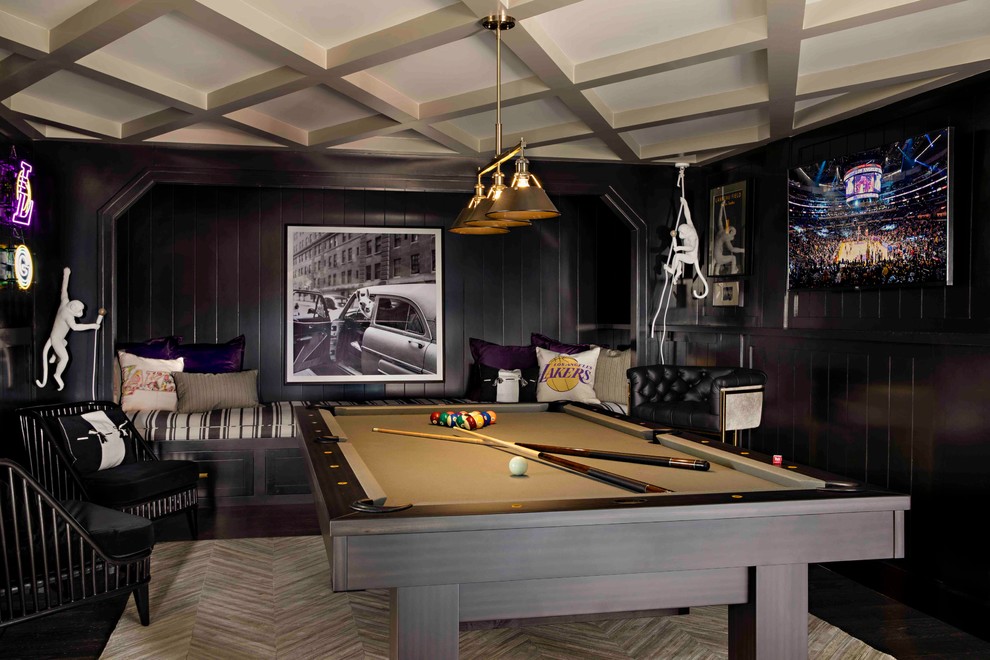 Modelo de sala de juegos en casa clásica renovada con paredes negras, suelo de madera oscura, televisor colgado en la pared y suelo marrón