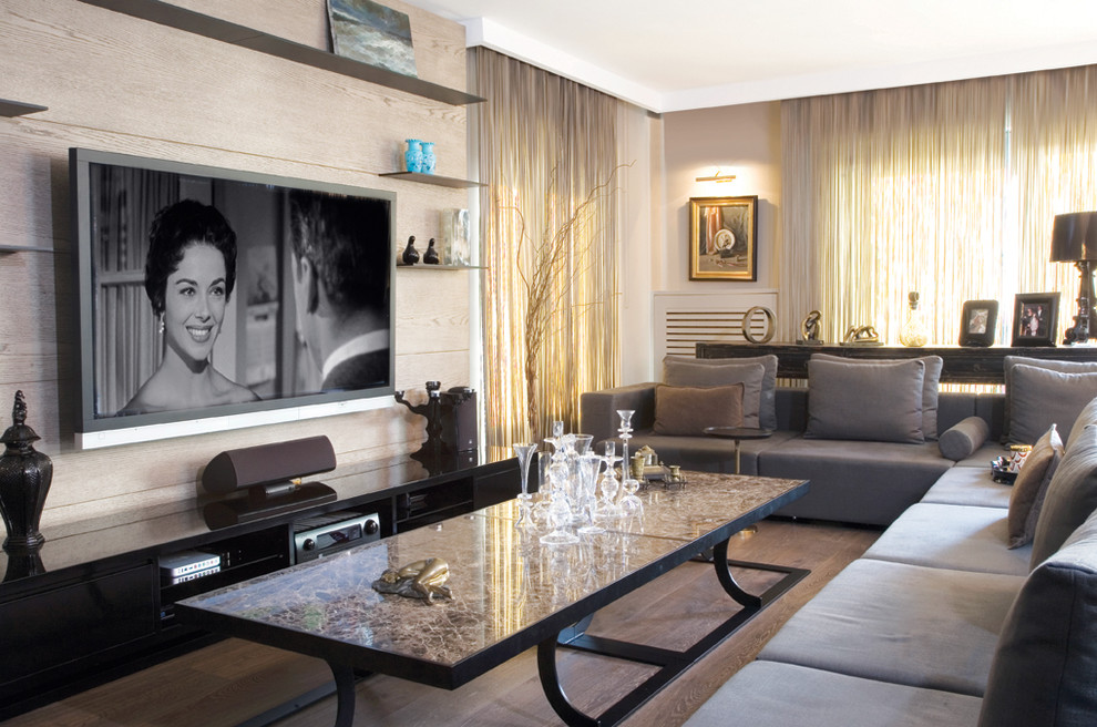 Modelo de sala de estar contemporánea con paredes beige, televisor colgado en la pared y suelo de madera en tonos medios