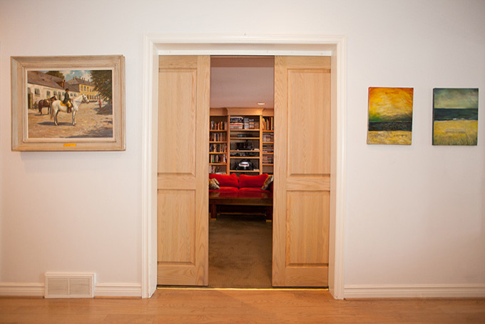 Foto de sala de estar con biblioteca tipo loft actual de tamaño medio con televisor colgado en la pared, paredes blancas, suelo de madera clara y suelo marrón