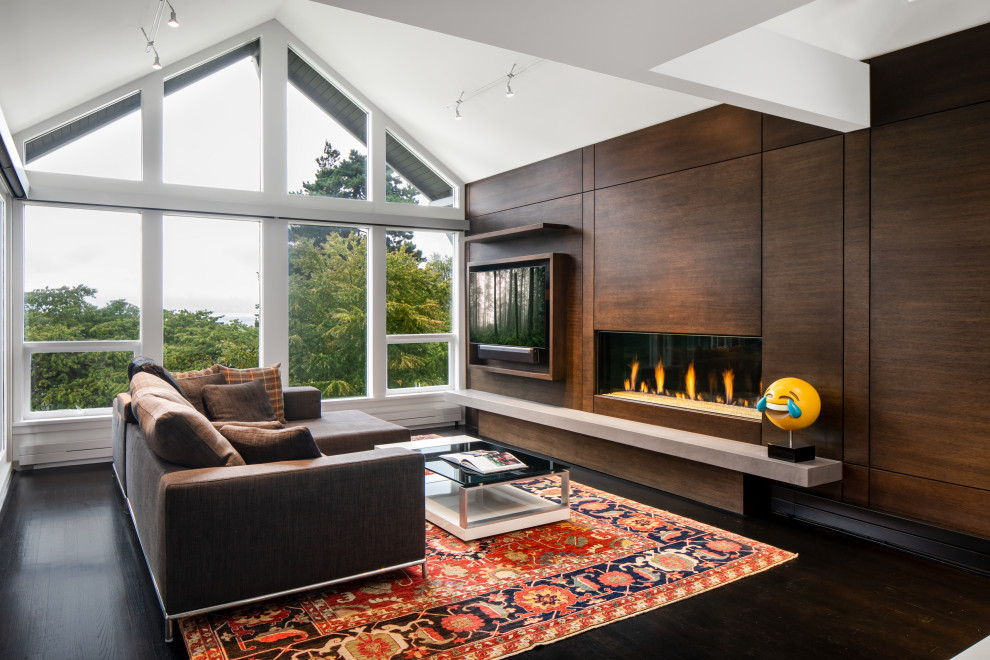 Inspiration for a mid-sized contemporary open concept dark wood floor, black floor, vaulted ceiling and wood wall family room remodel in Vancouver with white walls, a ribbon fireplace, a wood fireplace surround and a wall-mounted tv